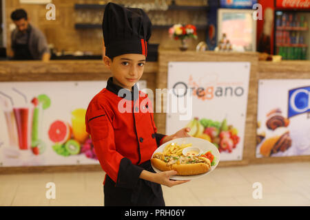 La ville de Gaza, bande de Gaza, territoire palestinien. 3e oct, 2018. Un garçon palestinien chef, Mohammed Abu Nada, 12, affiche sa cuisine dans un restaurant dans la ville de Gaza le 3 octobre 2018 Crédit : Mahmoud Ajjour/APA/Images/fil ZUMA Alamy Live News Banque D'Images