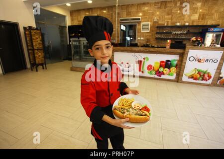 La ville de Gaza, bande de Gaza, territoire palestinien. 3e oct, 2018. Un garçon palestinien chef, Mohammed Abu Nada, 12, affiche sa cuisine dans un restaurant dans la ville de Gaza le 3 octobre 2018 Crédit : Mahmoud Ajjour/APA/Images/fil ZUMA Alamy Live News Banque D'Images