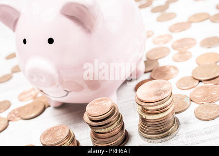 Pink Piggybank entouré par des crédits et les tas d'Euros Banque D'Images