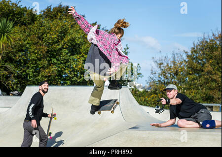 Un skateur femelle étant filmé l'exécution d'une tour d'antenne à des vagues de béton parc de skate à Newquay en Cornouailles. Banque D'Images