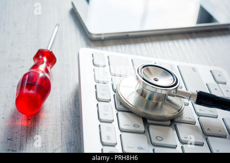 Stéthoscope sur un clavier à côté d'un tournevis et d'un Smartphone - Fixation Broken Computer Concept Banque D'Images