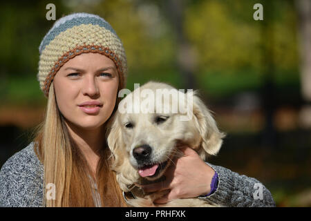 Portrait de jeune fille blonde, mignonne avec retriever dog posing together outdoors en automne journée ensoleillée Banque D'Images