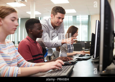 Aider les enseignants du secondaire de sexe masculin Student Working in Computer Class Banque D'Images