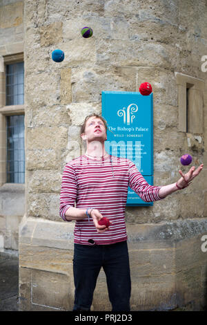 Un artiste de rue juggling au Wells Place du marché . Il est aussi un musicien qui joue d'une guitare et violon. Wells, Somerset, UK Banque D'Images