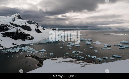 Les icebergs éparpillés dans la baie avec yacht ancré, Cuverville Island, Antarctic Peninsula Banque D'Images