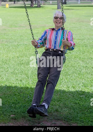 Un citoyen senior woman enjoying balançant dans un parc public à l'ouest jusqu'au Texas. Banque D'Images