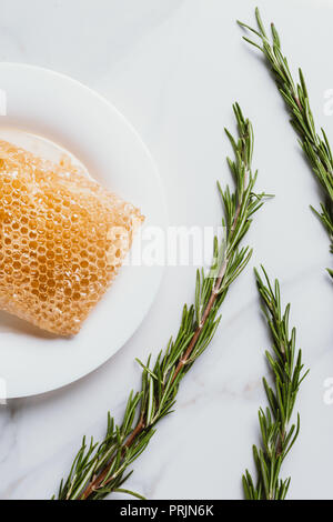 Portrait de plaque avec miel et romarin sur table de marbre Banque D'Images