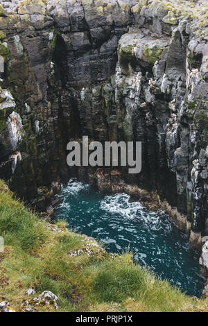 Vue aérienne de la falaise rocheuse et s'écraser les vagues bleu en Islande Banque D'Images