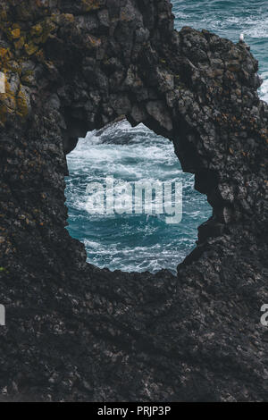 Voir des vagues de l'océan à travers le trou de la falaise,, Islande Banque D'Images