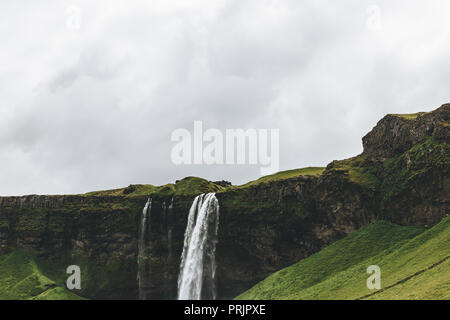 Vue panoramique du paysage avec cascade de Seljalandsfoss en highlands sous ciel nuageux en Islande Banque D'Images