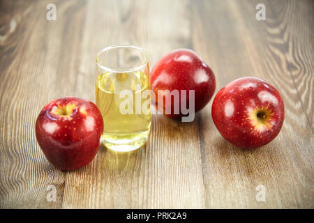 Trois pommes et un verre de jus de pomme sur la surface en bois dur. Banque D'Images