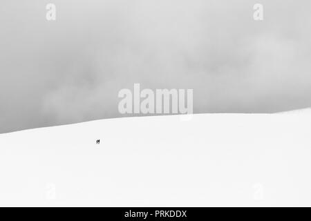 Un très lointain de minimaliste deux personnes au-dessus d'une montagne couverte de neige Banque D'Images