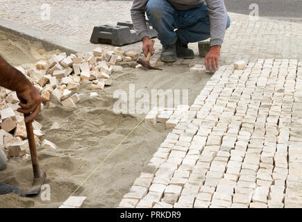 L'installation de blocs de pierre sur les travailleurs de rue de la chaussée ou le trottoir. Banque D'Images