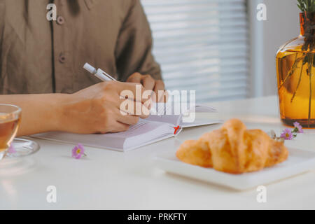 Portrait d'un homme assis à une table en bois blanc vintage et d'un plateau tout en travaillant avec le bloc-notes Banque D'Images