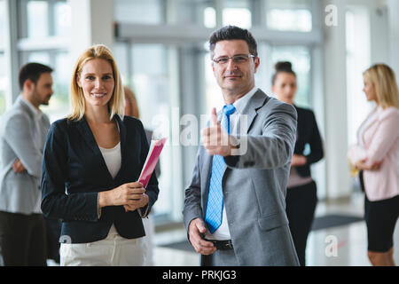 Smiling business team standing alors que giving Thumbs up à nouveau car showroom Banque D'Images