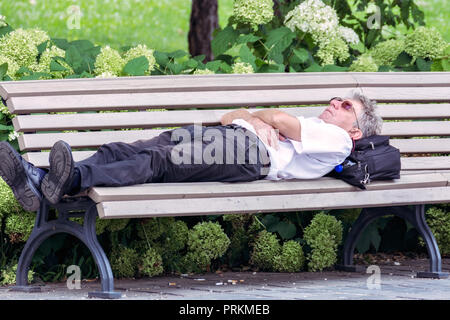 Budapest, Hongrie, 4 juillet : un homme en chemise blanche fixer pour se reposer sur un banc dans la rue de la ville de Budapest le 4 juillet 2018. Banque D'Images