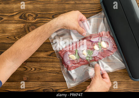 Homme adulte non identifiés en plastique coulissante Les viandes emballées avec l'oignon et l'ail dans black machine pour préserver la viande Banque D'Images