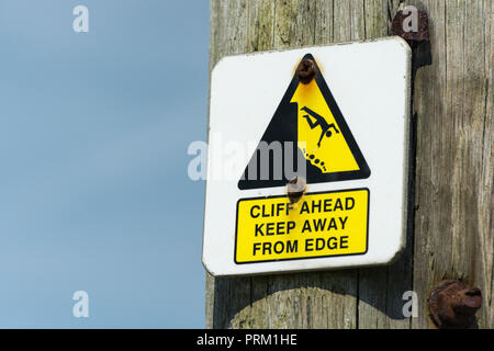 Un triangle jaune d'avertissement mettant en évidence le bord d'une falaise dangereuse à proximité. Tenir éloigné du concept de bord, tomber, tomber le pictogramme de l'homme en chute libre. Banque D'Images