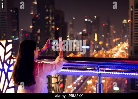 Girl taking a photo de Dubai cityscape at night Banque D'Images