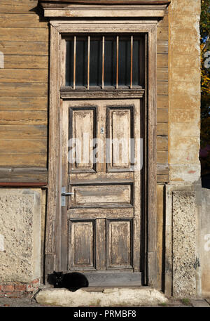 Chat noir dort sur un seuil de la vieille maison en bois. Banque D'Images