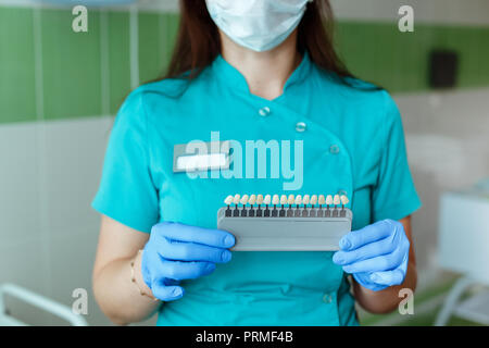 Dentiste tenant dans les mains correspondant aux nuances de couleur ou de l'implant ou le processus de blanchiment des dents. Banque D'Images
