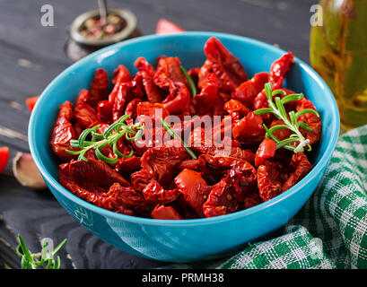 Tomates séchées au soleil avec des herbes et l'ail dans un bol sur la table en bois. Cuisine italienne. Banque D'Images