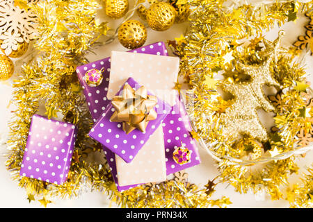 Beige élégante et violet (pourpre) pile de cadeaux avec le ruban d'or autour de la décoration de Noël, la nouvelle année se présente avec golden Garland et de guirlandes Banque D'Images