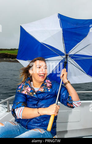 Jeune femme en riant sur un bateau avec parapluie cassé Banque D'Images