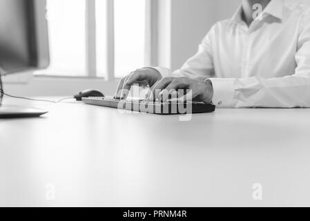 Image en noir et blanc de portrait à son bureau Bureau de la saisie sur clavier d'ordinateur. Banque D'Images