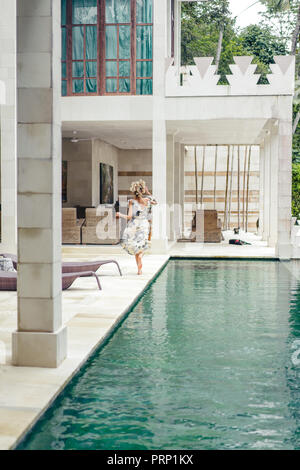 Vue arrière de la femme en belle robe d'exécution proche piscine à la villa Banque D'Images