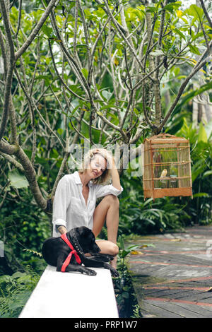 Belle blonde woman sur terrasse avec chien noir, Ubud, Bali, Indonésie Banque D'Images