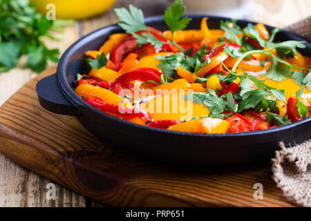 Shakshuka, œufs frits cuits dans la sauce tomate et les poivrons dans la poêle en fonte sur table en bois rustique Banque D'Images