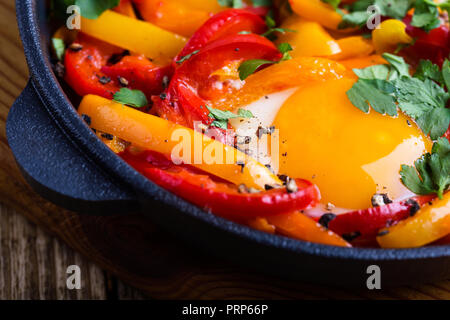 Shakshuka, œufs frits cuits dans la sauce tomate et les poivrons dans la poêle en fonte sur table en bois rustique Banque D'Images