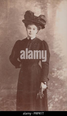 * L'ère d'Edwardian Vintage Photo d'une jeune femme élégamment vêtue portant un chapeau et gants fantaisie Holding Banque D'Images