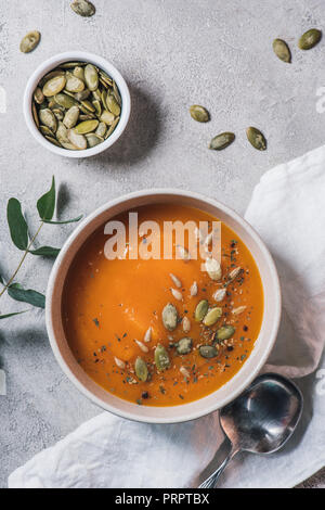 Vue de dessus du bol à soupe de potiron et les graines sur la table Banque D'Images
