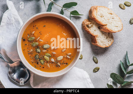 Vue de dessus du bol avec la soupe de potiron avec des graines et du pain sur la table Banque D'Images