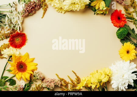 Mise à plat avec diverses belles fleurs arrangement avec un espace vide au milieu fond beige Banque D'Images