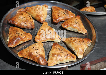 Les galettes traditionnelles de l'ouzbek (SAMSA) avec la viande de poulet, couché sur un grand plat de métal Banque D'Images