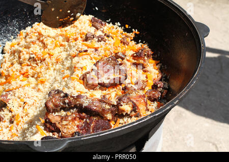 Pilaf ouzbek traditionnel avec viande d'agneau cuite dans un grand chaudron Banque D'Images