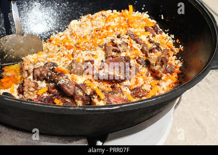 Pilaf ouzbek traditionnel avec viande d'agneau cuite dans un grand chaudron Banque D'Images