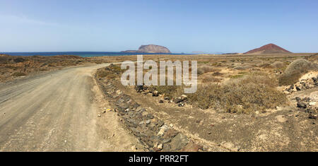 Lanzarote, Canaries : la route de la plage Playa de las Conchas et le volcan Montana Bermeja écarlate (montagne) de l'île de La Graciosa Banque D'Images