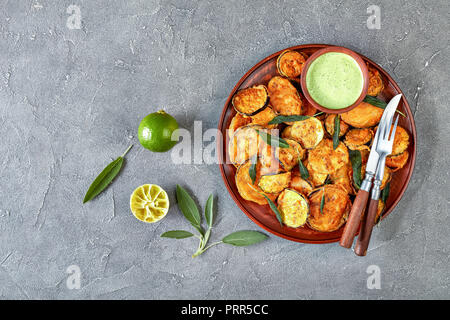 Aubergine aubergine frite pané tranches sur une plaque de faïence avec du yaourt persil trempant dans un bol d'argile sur une table en béton avec de la chaux et des s Banque D'Images