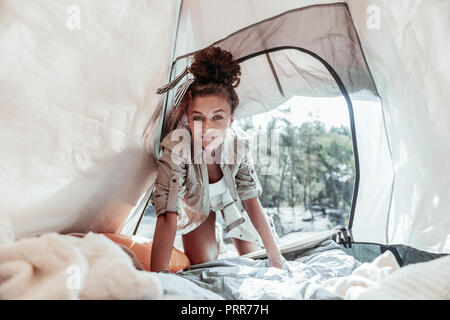 Jeune femme brune portant chemise kaki entrant belle grande tente dans la forêt Banque D'Images