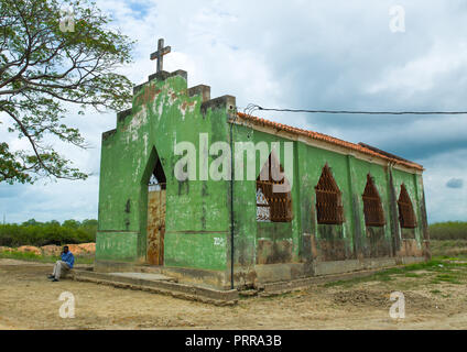 Homme angolais s'asseoir en face d'une église verte abandonnés, la province de Malanje, Calandula, Angola Banque D'Images