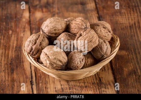 Les noix dans un bol de pieux sur table en bois rétro arrière-plan. Concept alimentaire. Close up, selective focus Banque D'Images