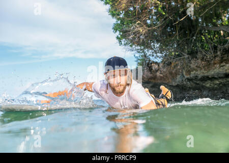 Homme sérieux natation surfer sur le surf de l'océan en bord de plage de Nusa Dua, Bali, Indonésie Banque D'Images