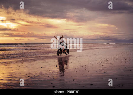 Vue arrière de l'heureux couple riding on Ocean Beach Banque D'Images