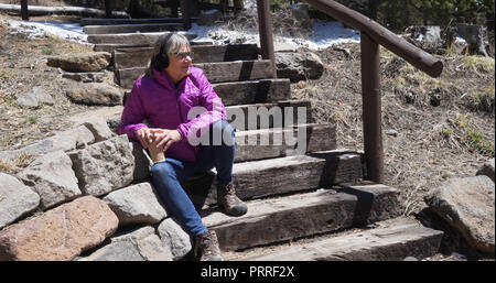 Heureux vieille femme assis sur des escaliers à l'extérieur des forêts en souriant Banque D'Images