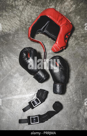 Vue de dessus des gants de boxe et casque avec serrage poignet allongé sur une surface en béton Banque D'Images