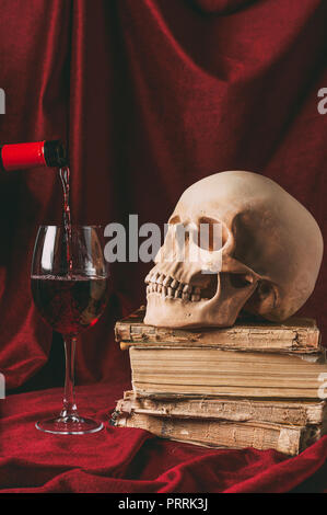 Vin rouge, halloween crâne sur d'anciens livres sur tissu rouge Banque D'Images